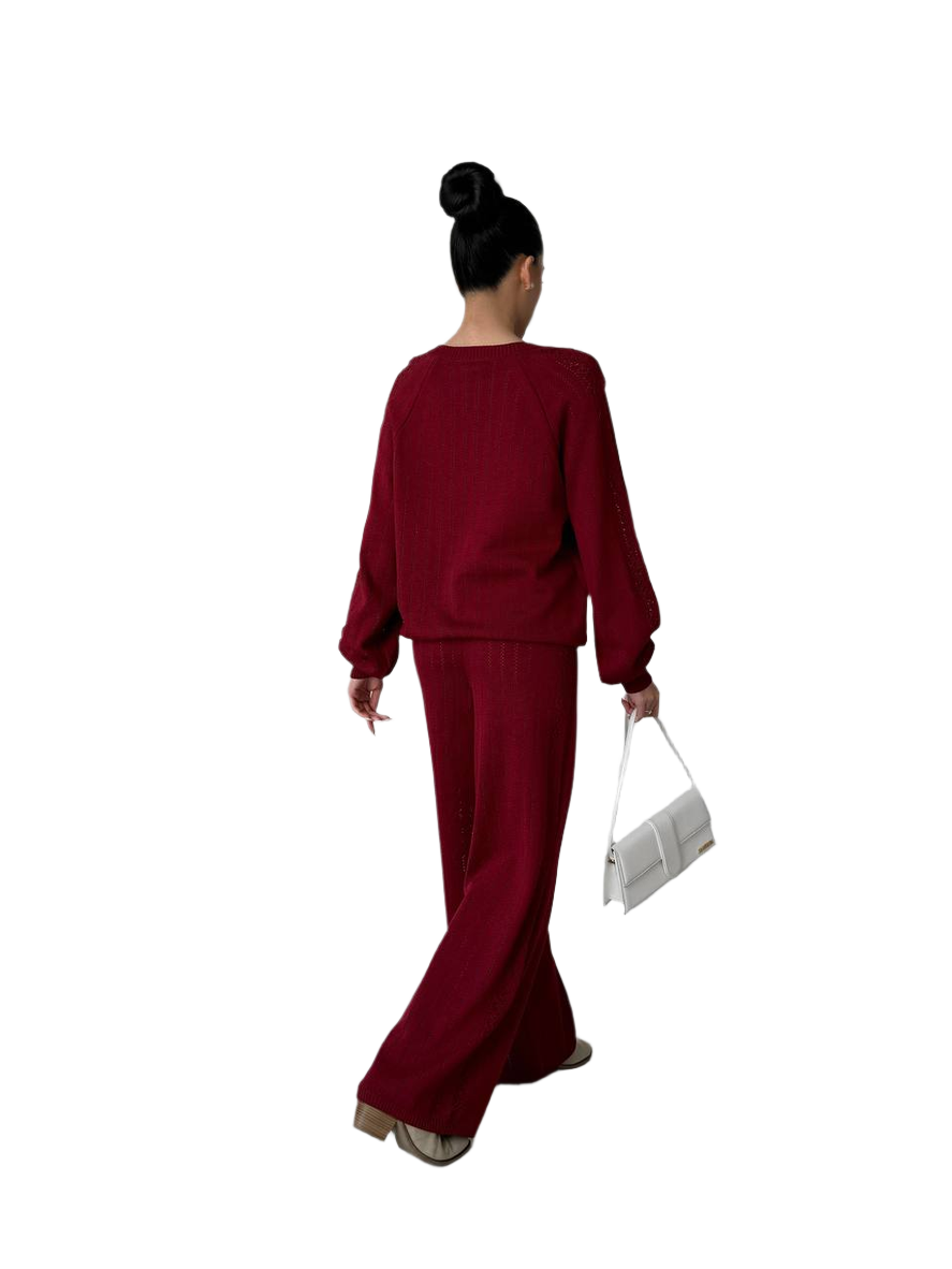 Person wearing a burgundy outfit holding a white clutch on a white background
