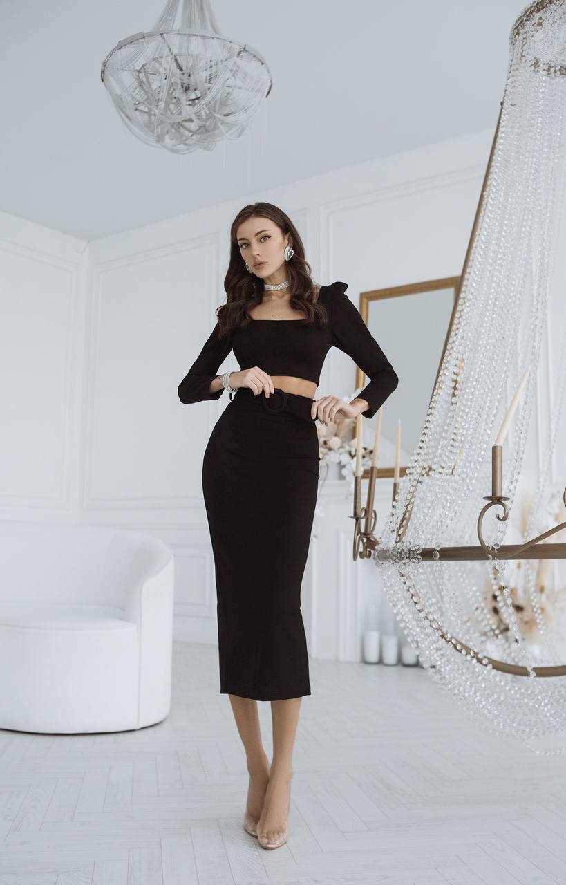 Woman in a black dress standing in a stylish room with chandeliers.