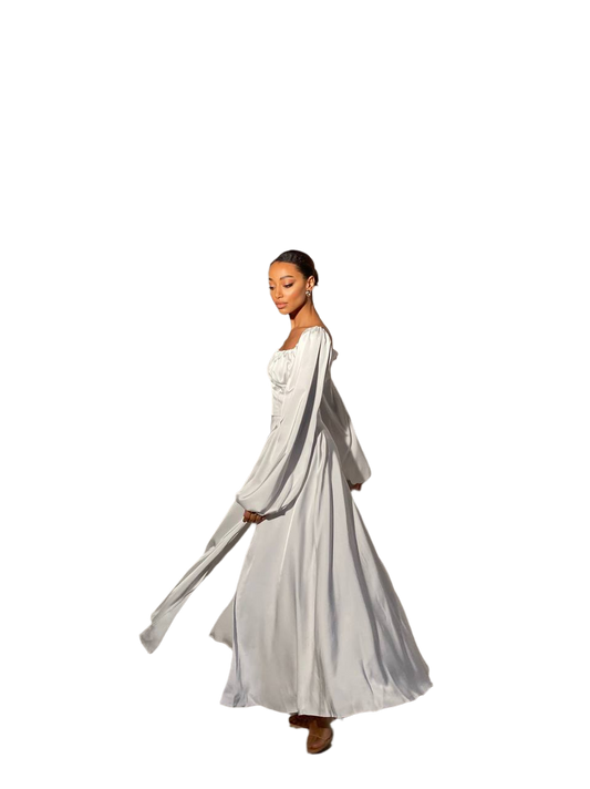 Woman wearing a long, light-colored dress with a flowing train on a white background
