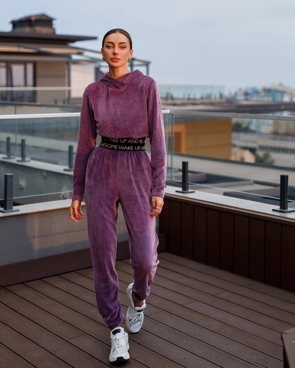 Person wearing a purple tracksuit on a rooftop with a cityscape background