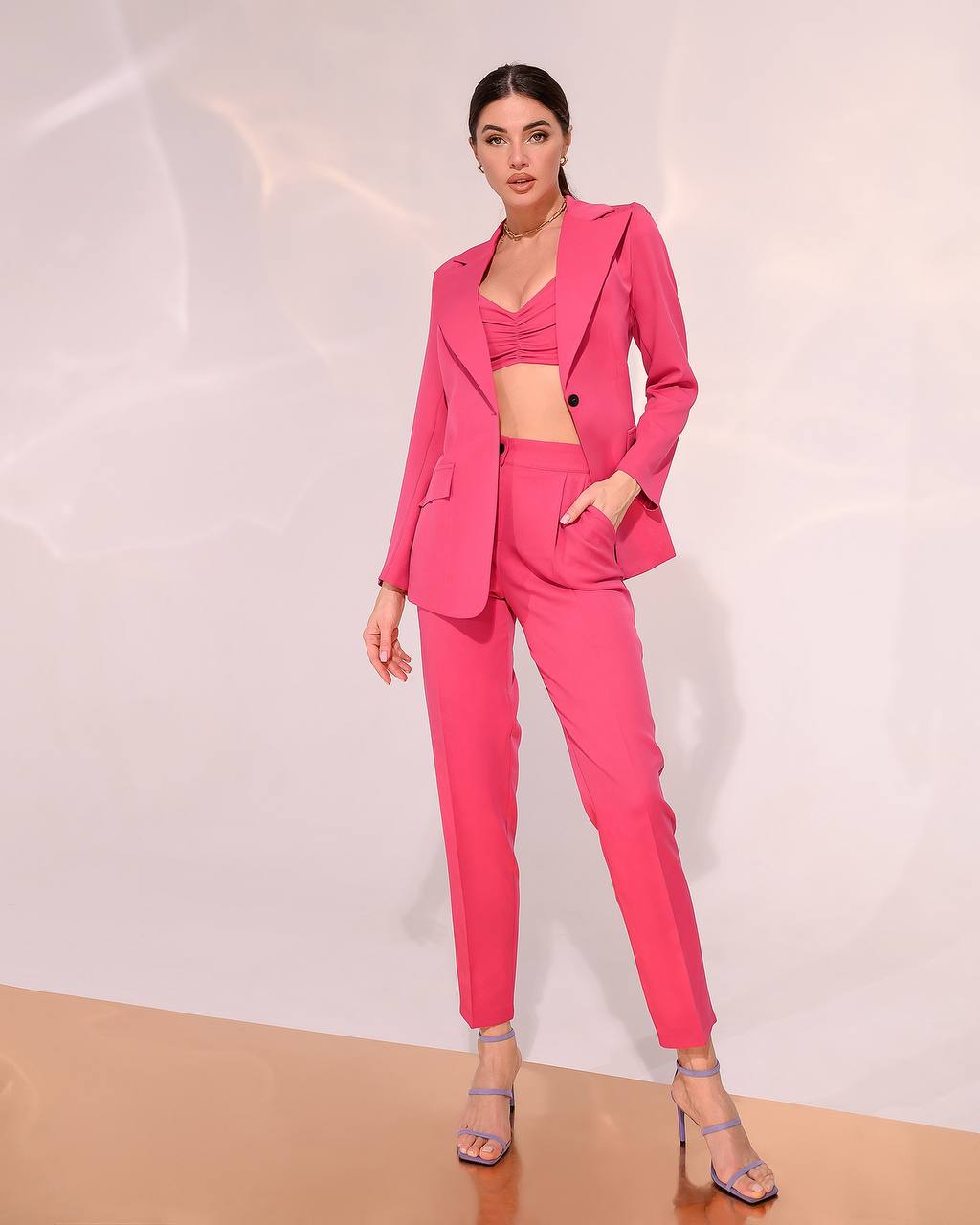 Woman wearing a bright pink suit against a white background