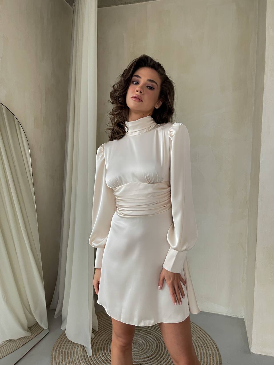 Woman in a white dress standing in a room with neutral decor