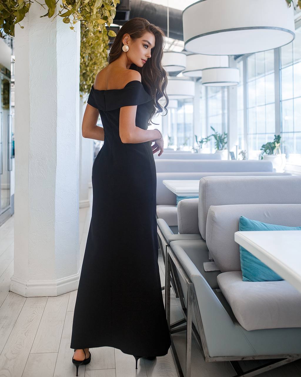 Woman in a black evening gown standing in a modern restaurant.