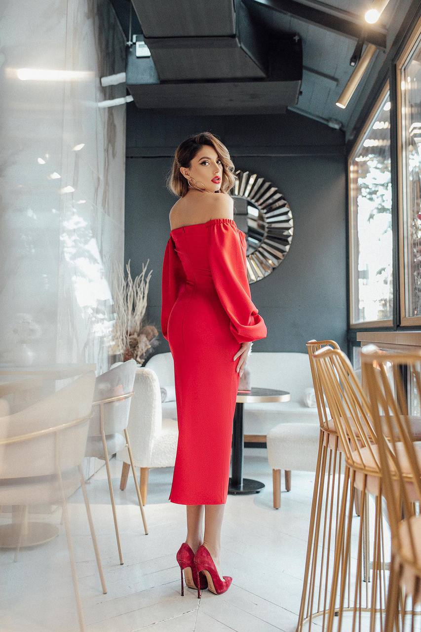 Woman in a red dress standing in a modern restaurant interior.
