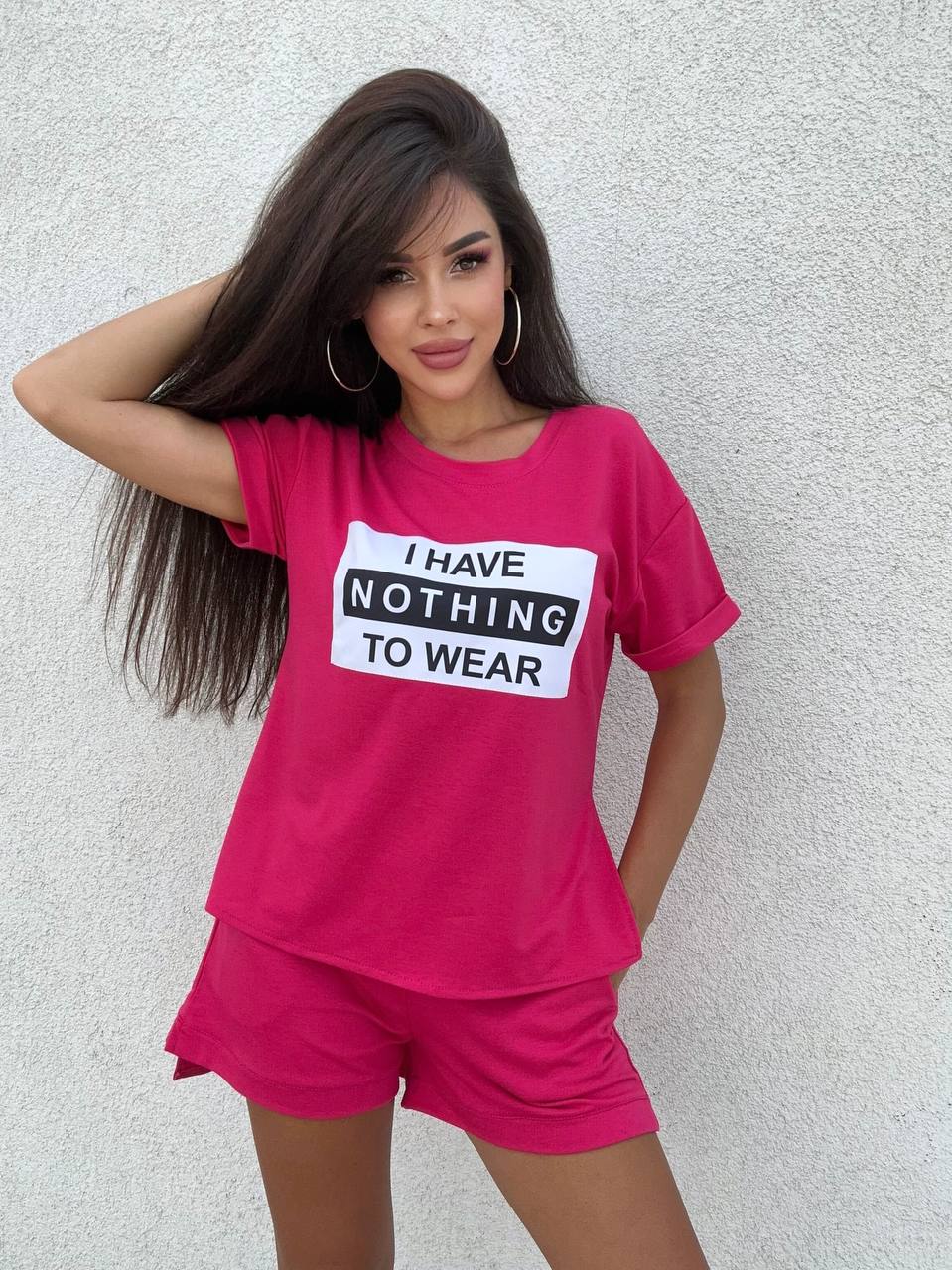 Woman wearing a pink outfit with a shirt and shorts, featuring text 'I HAVE NOTHING TO WEAR' on a plain background.