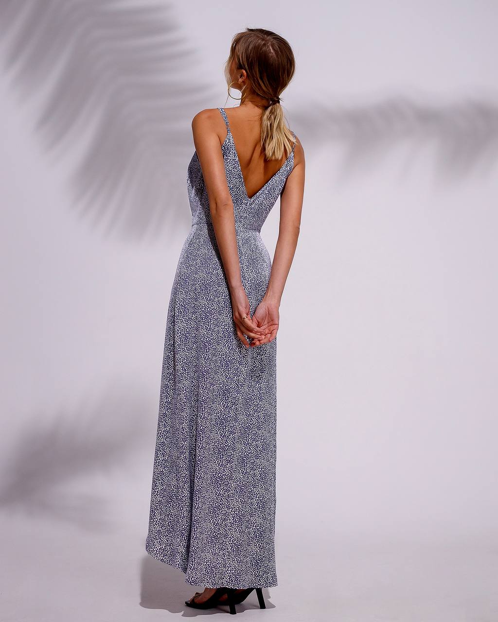 Woman wearing a long, patterned dress with a plain background