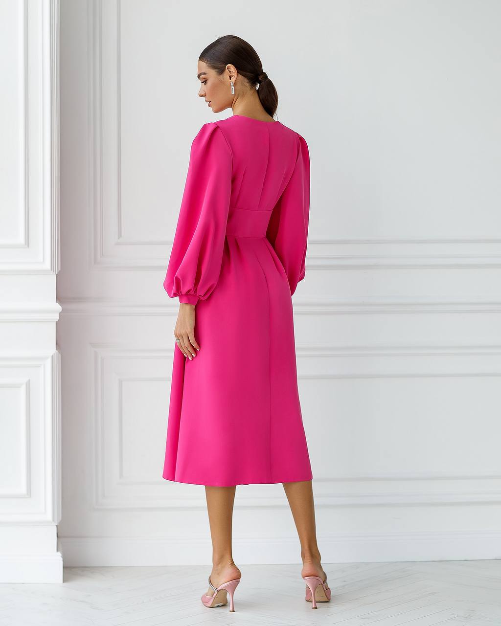 Woman wearing a bright pink dress in a minimalistic setting