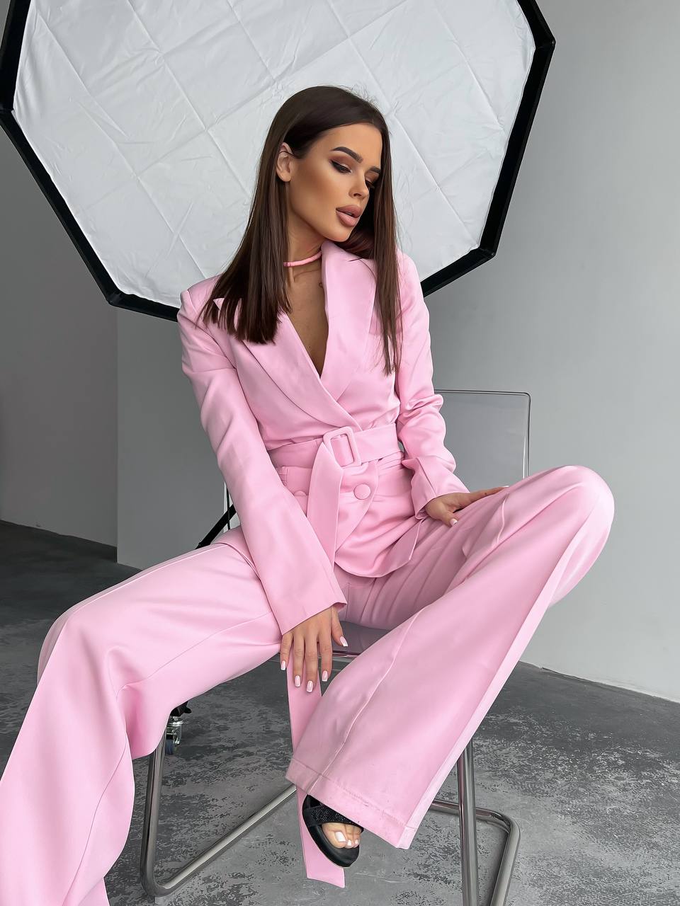 Woman in a pink suit sitting on a chair with a softbox light in the background