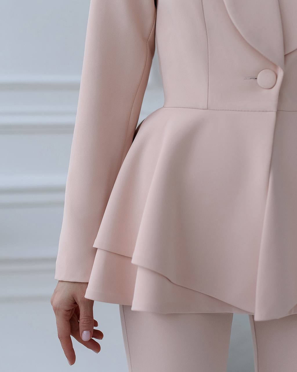 Light pink suit with a peplum skirt on a neutral background