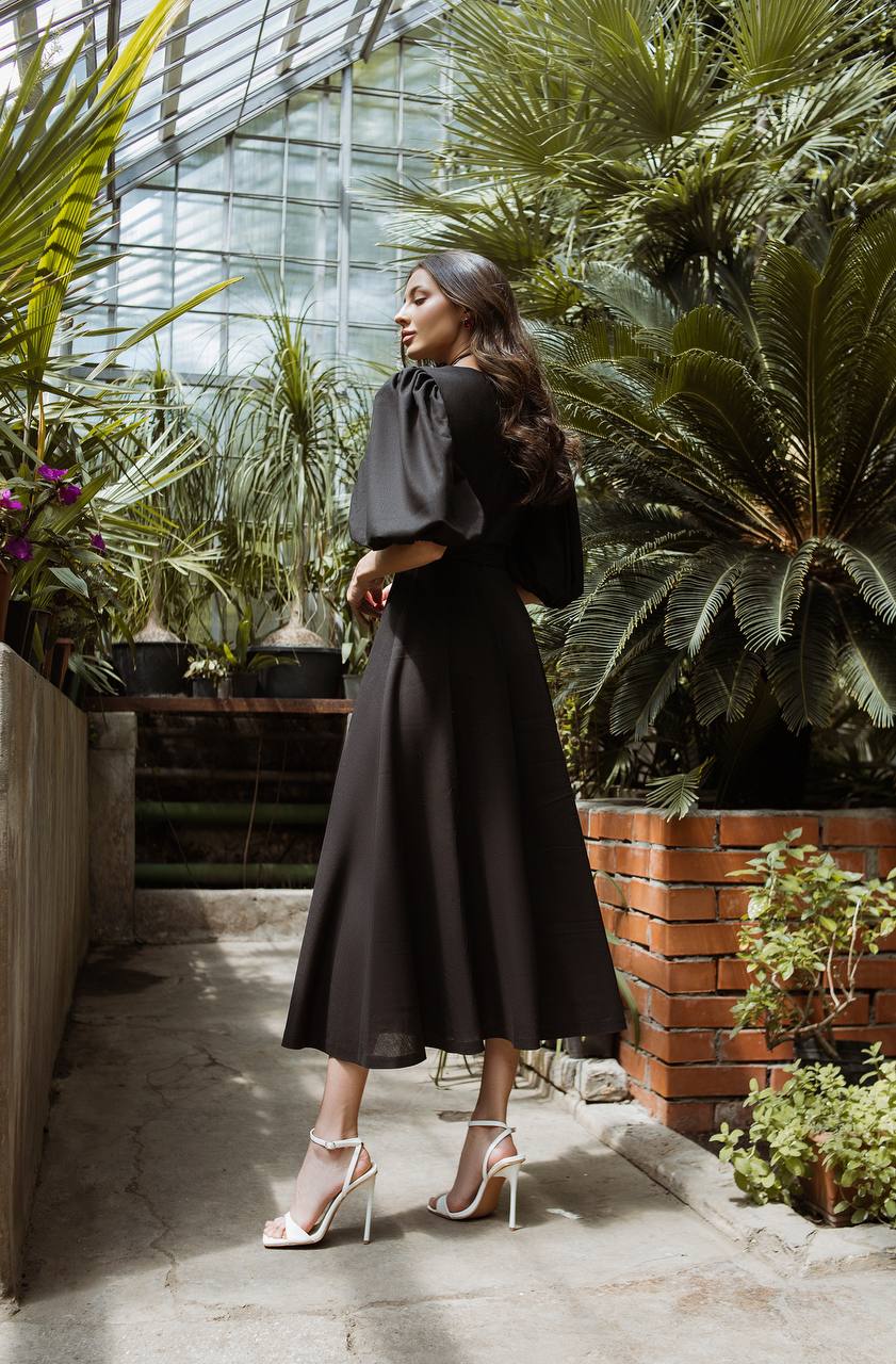 Woman in a black outfit standing in a greenhouse with plants around