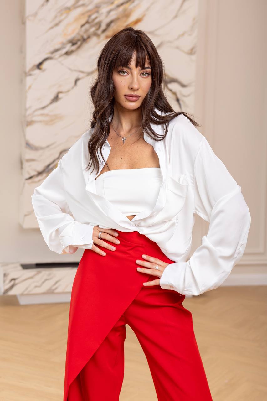Woman wearing a white blouse and red pants in an indoor setting