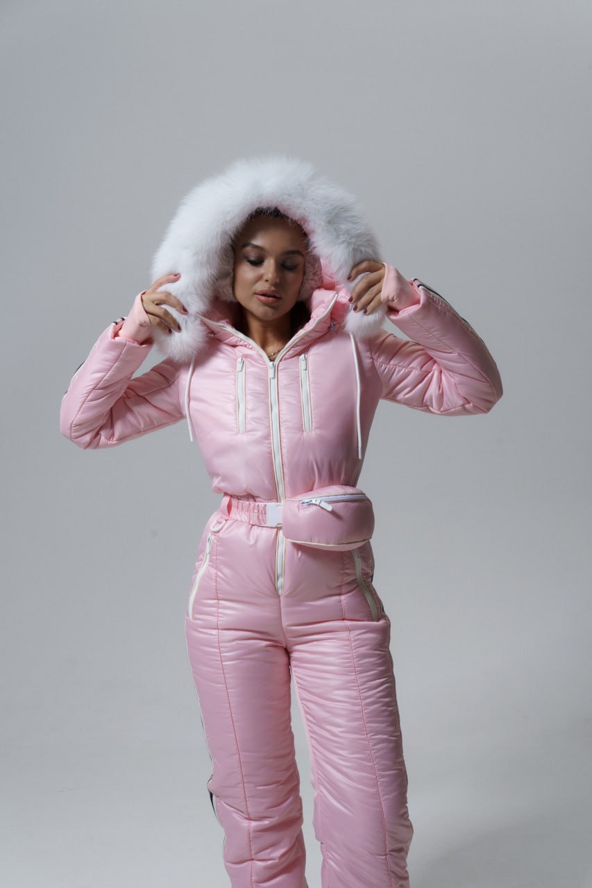 Person wearing a pink puffer suit with a white fur hood on a gray background