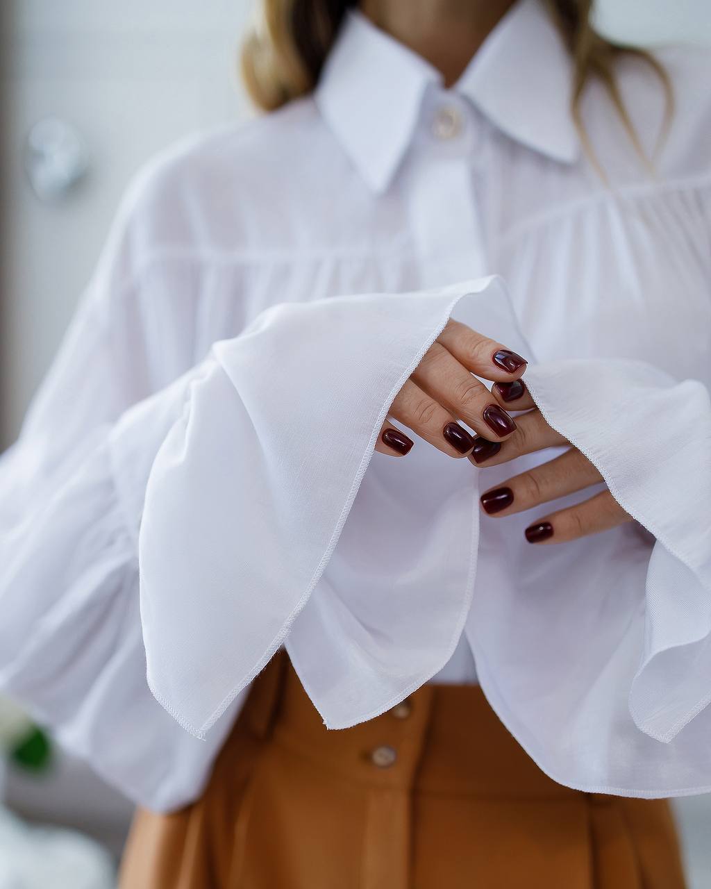 Close-up of a person wearing a white blouse with ruffled sleeves.