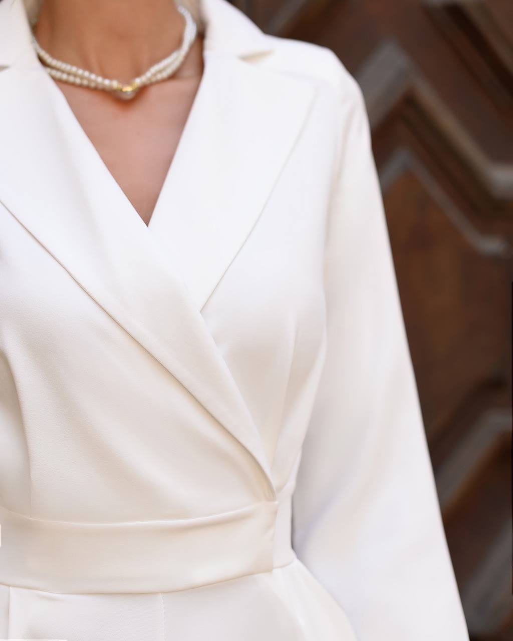 White dress with a pearl necklace against a blurred background