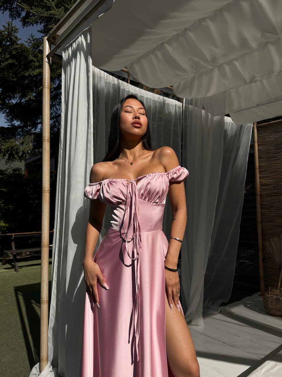 Woman in a pink dress standing outdoors with a white canopy in the background