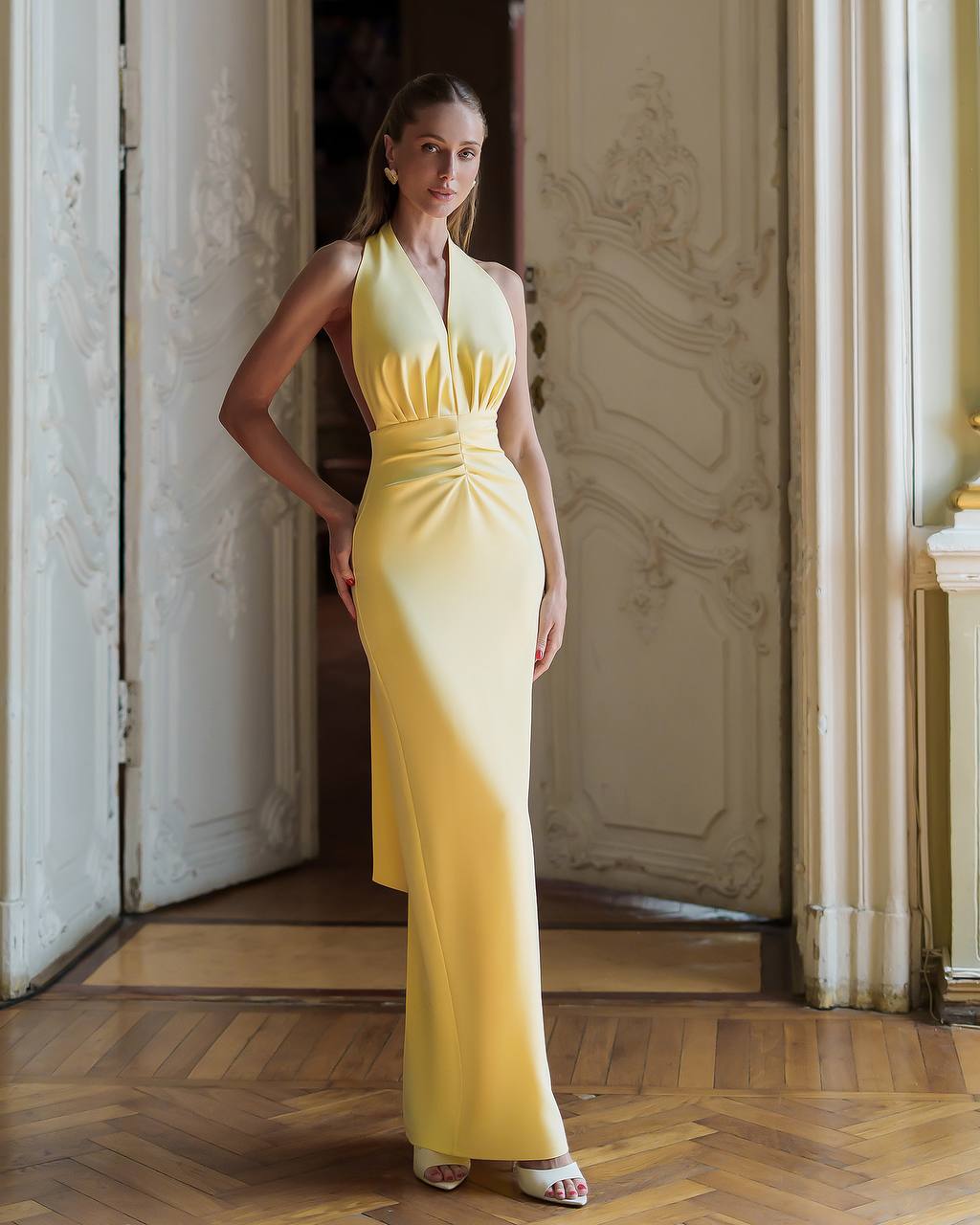 Woman in a yellow dress standing in an elegant interior setting
