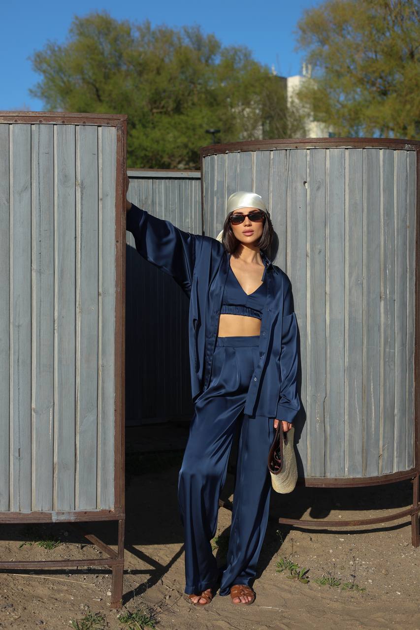 Person wearing a blue outfit standing next to metal tanks outdoors