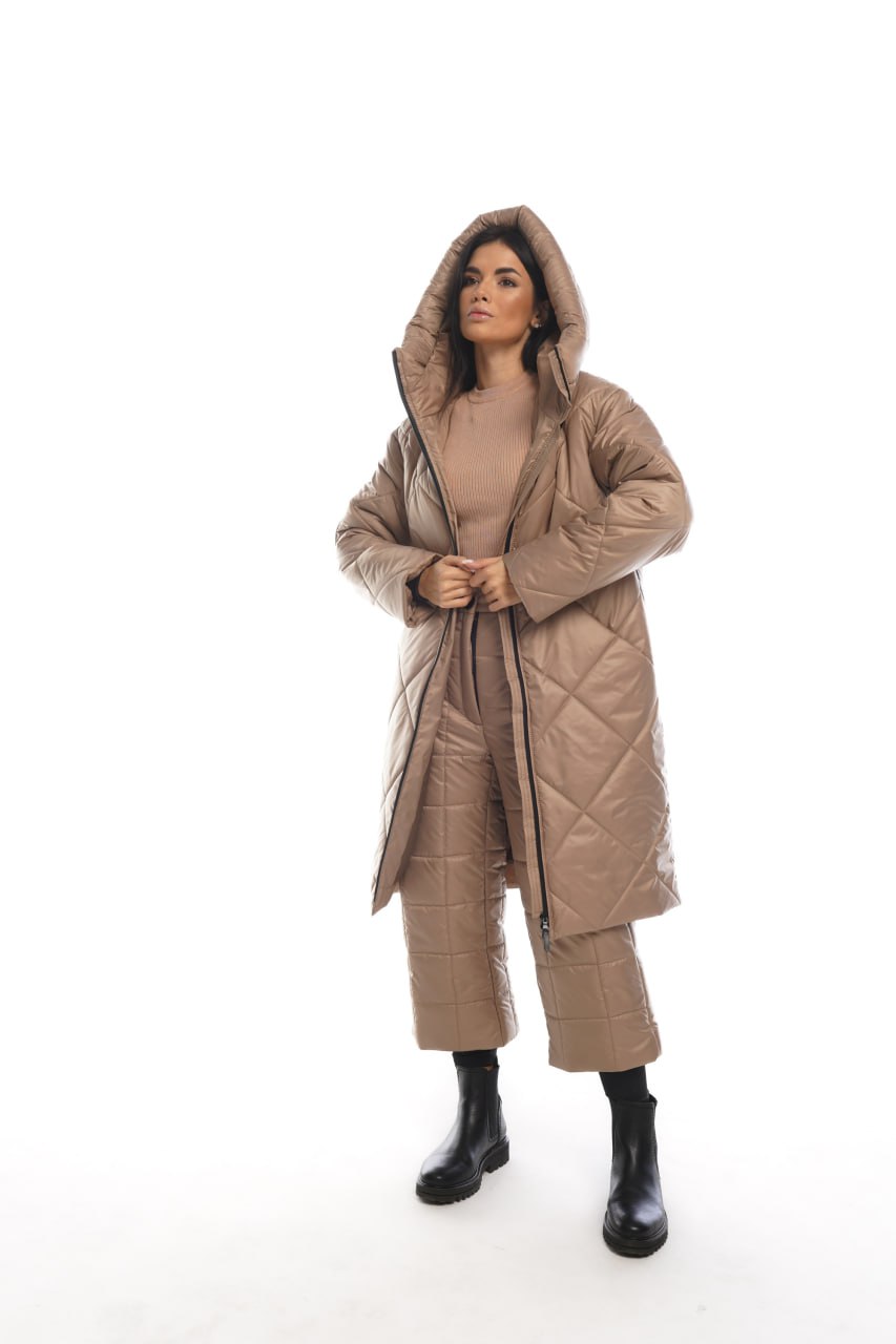Woman wearing a long quilted beige coat on a white background