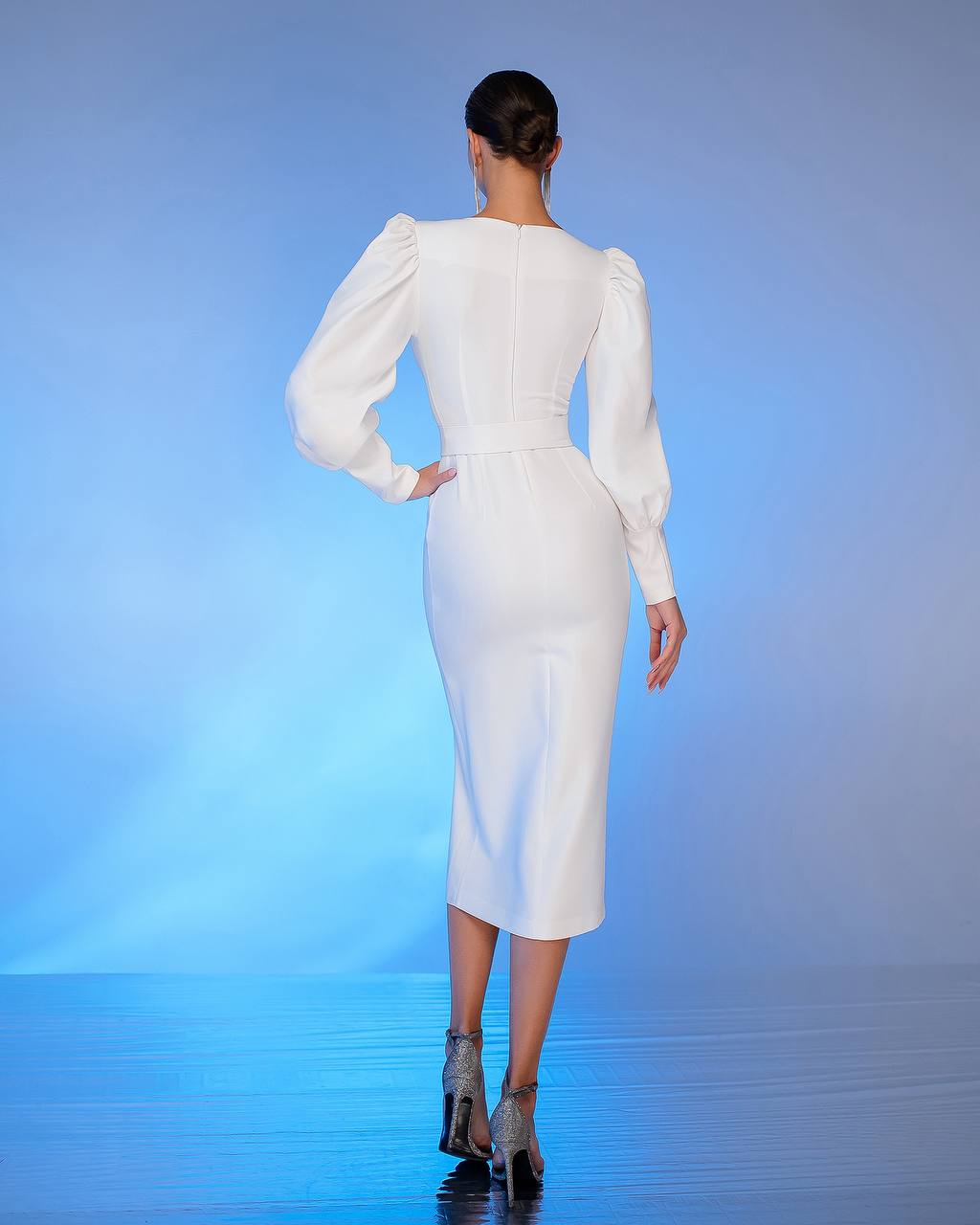 Woman wearing a white dress with puffed sleeves on a blue gradient background