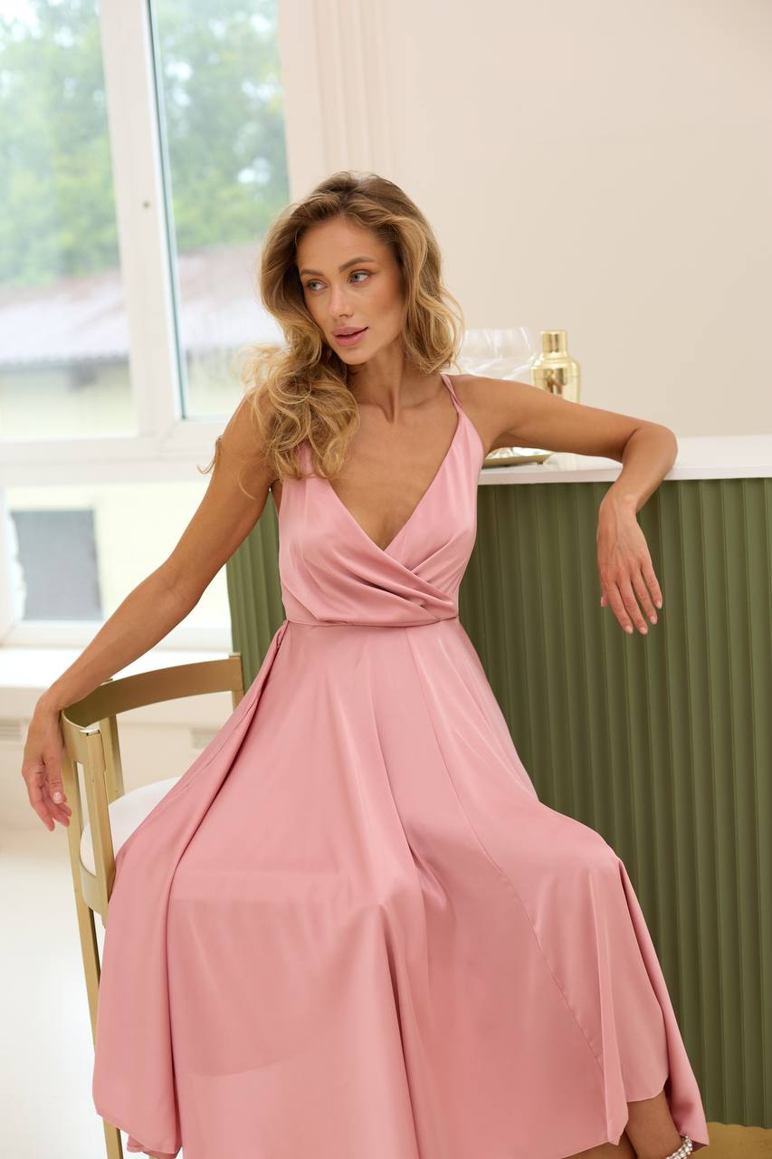 Woman in a pink dress sitting on a chair indoors.