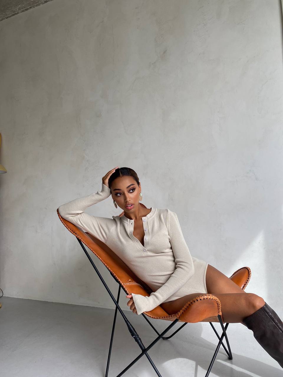 Woman sitting on a modern chair against a plain wall
