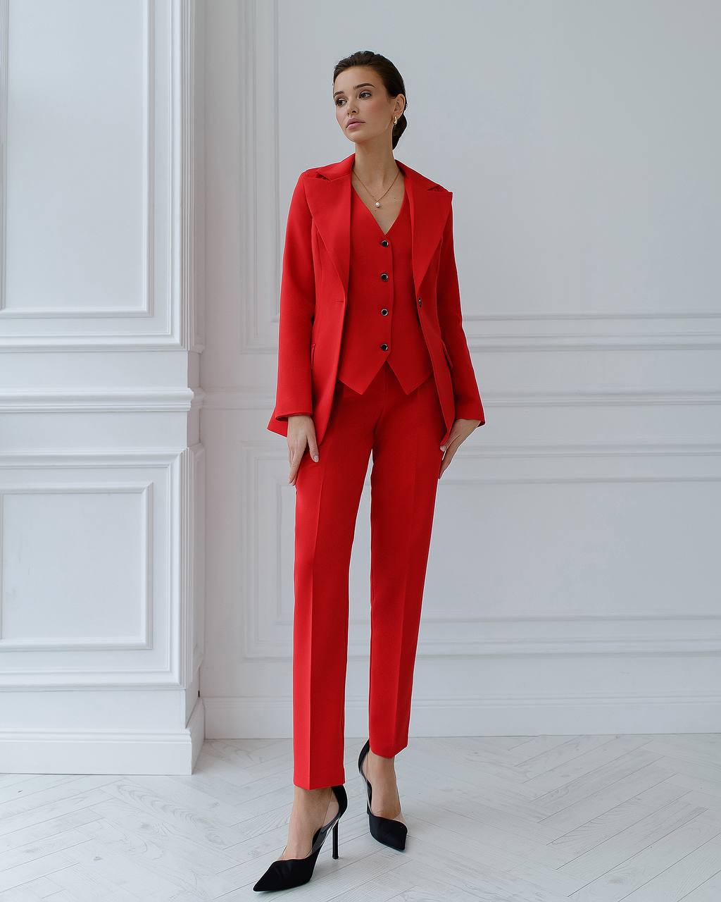 Woman wearing a red suit standing against a white wall