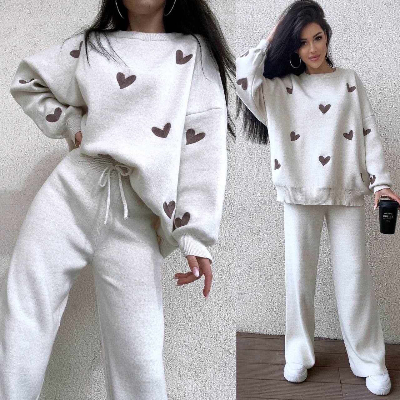 White sweatshirt and pants set with heart patterns worn by a person against a neutral background