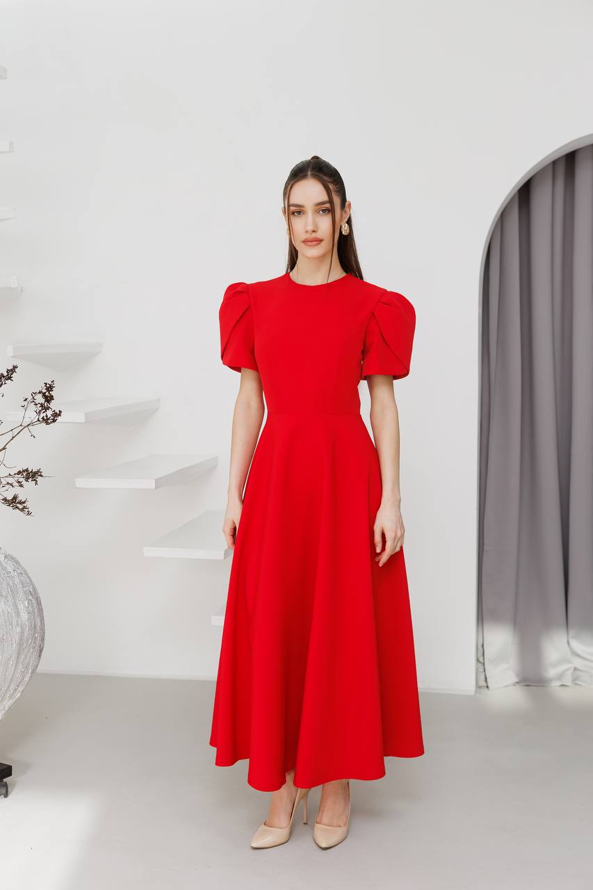 Woman wearing a red dress with puff sleeves in a minimalistic setting