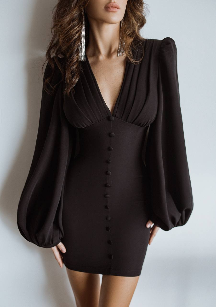 Black dress with puffed sleeves worn by a model against a plain background