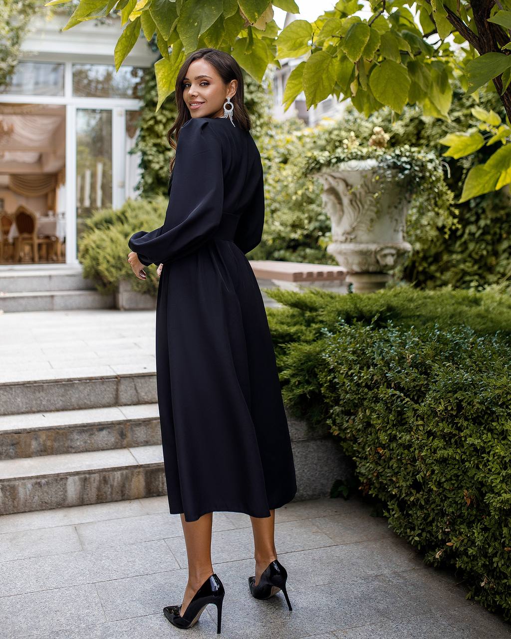 Woman in a black dress standing in a garden setting