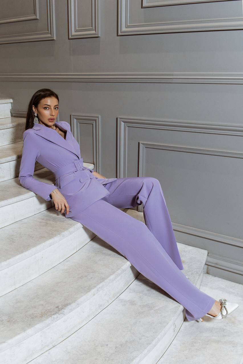 Woman in a lavender suit sitting on a staircase with a gray wall background