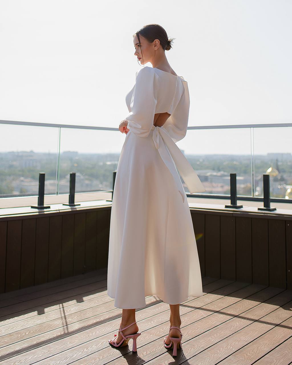Woman in a white dress standing on a rooftop with a cityscape view