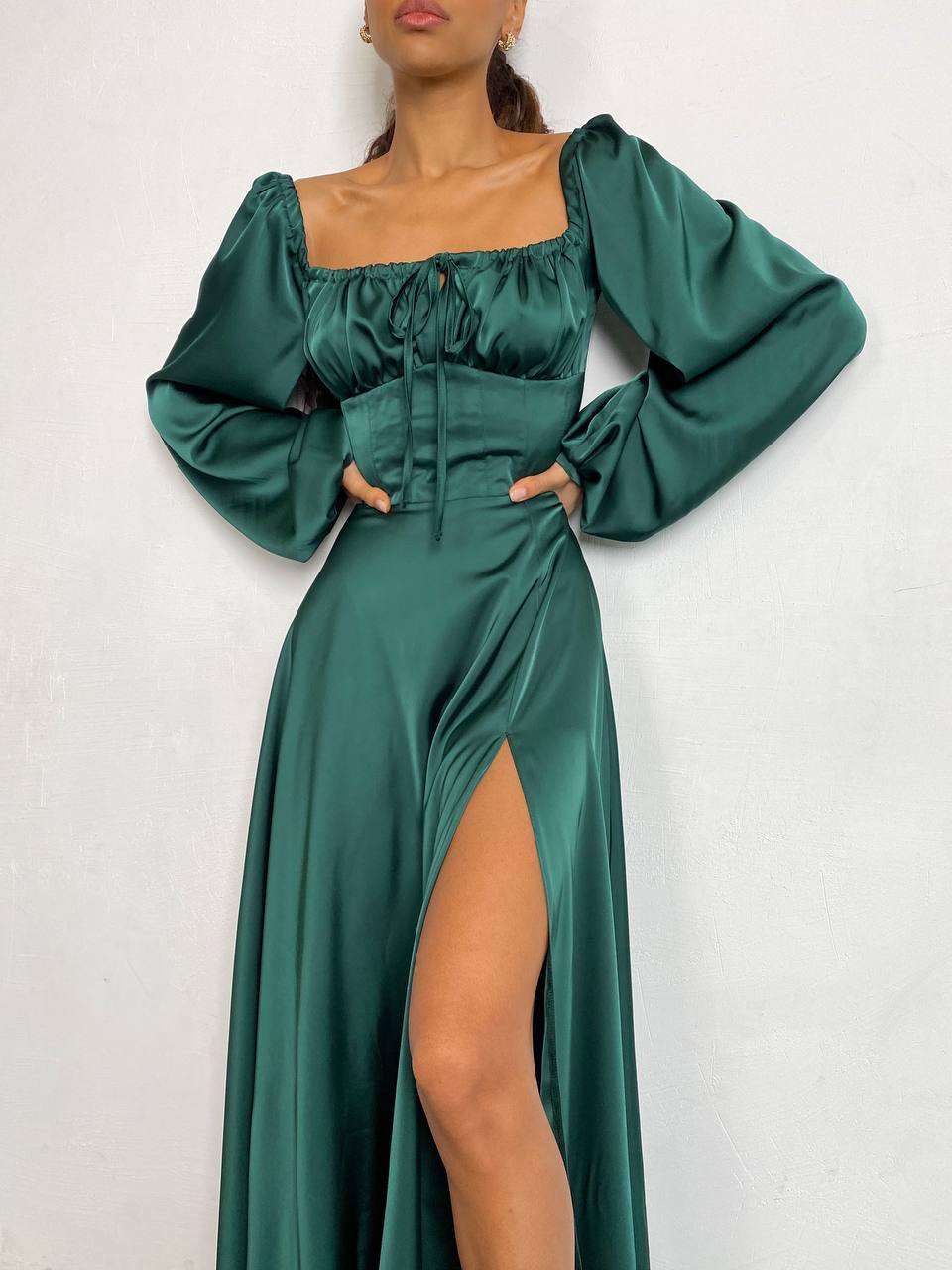 Green satin dress with long sleeves and a high slit on a white background