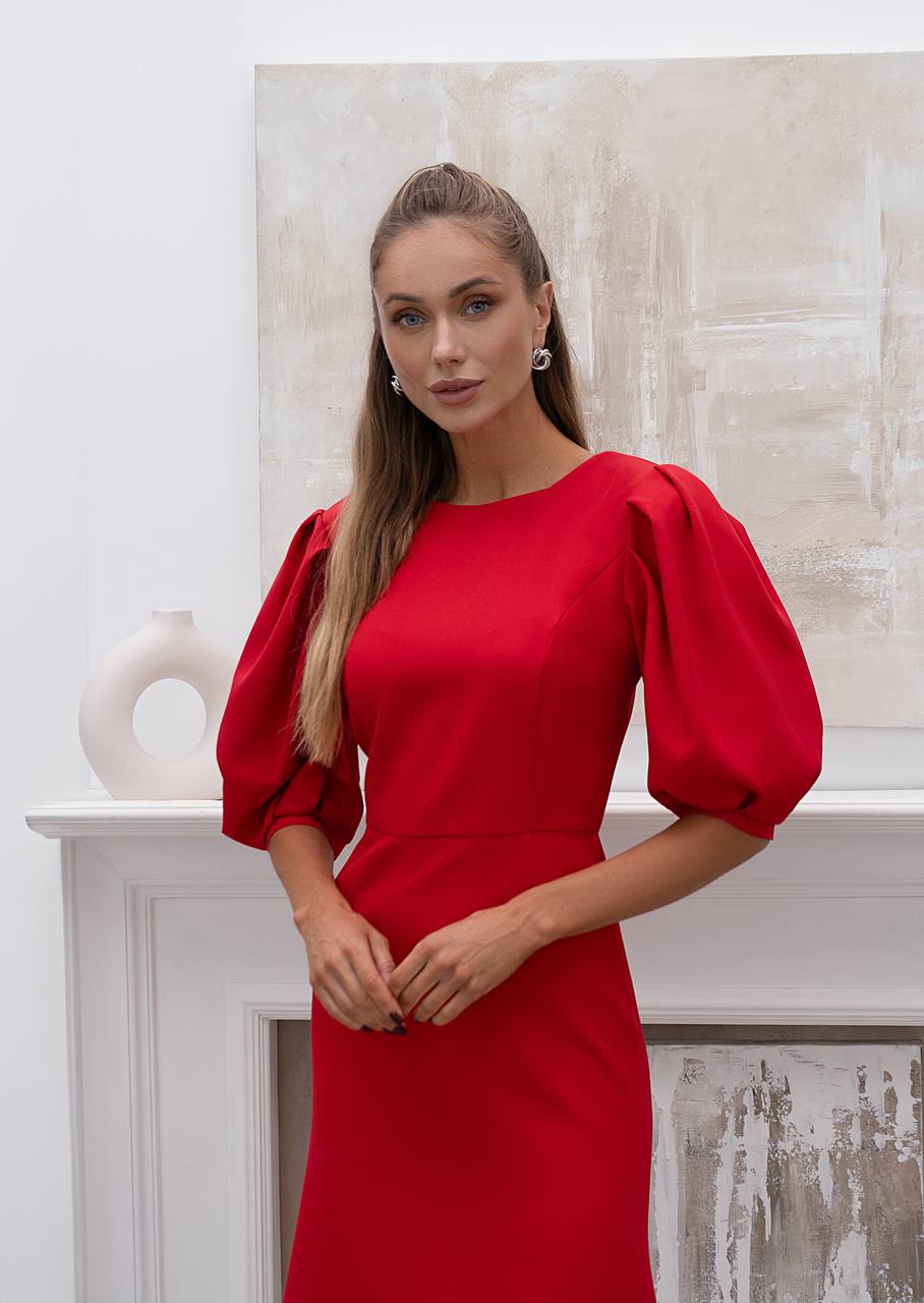 Woman wearing a red dress with puffed sleeves in an indoor setting.