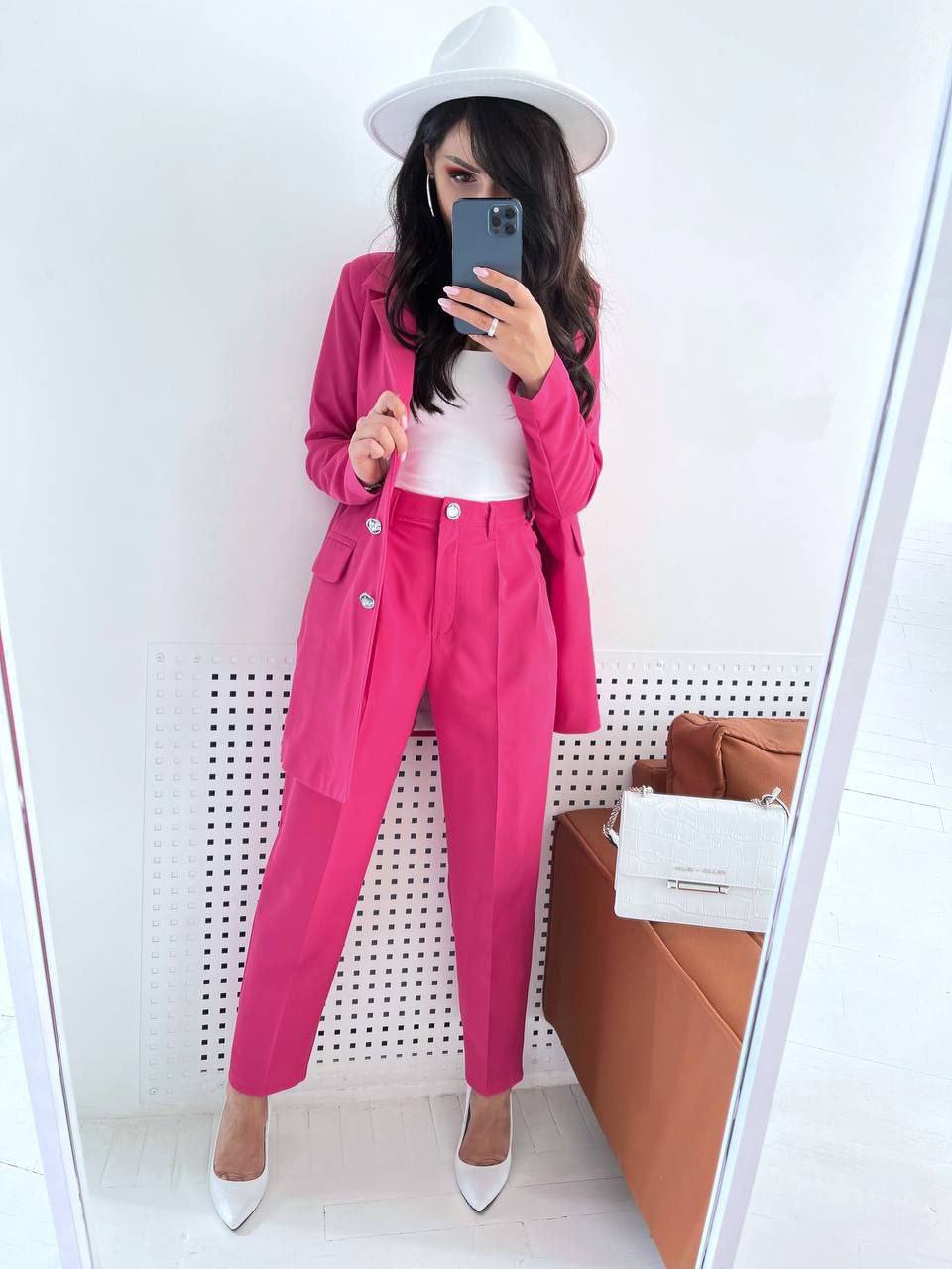 Person wearing a bright pink outfit with a white hat, standing in front of a mirror.