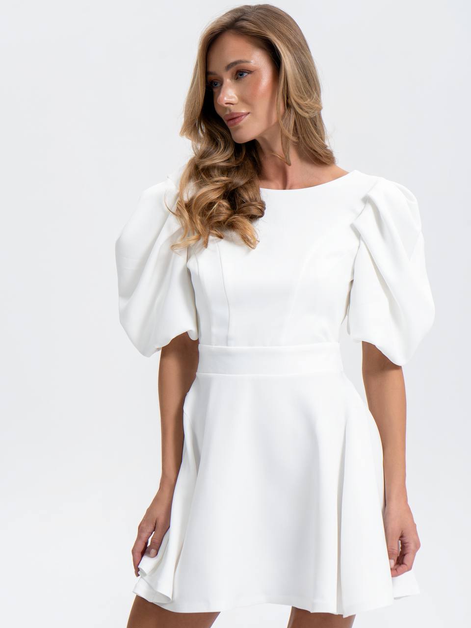 Woman wearing a white dress with puff sleeves on a white background
