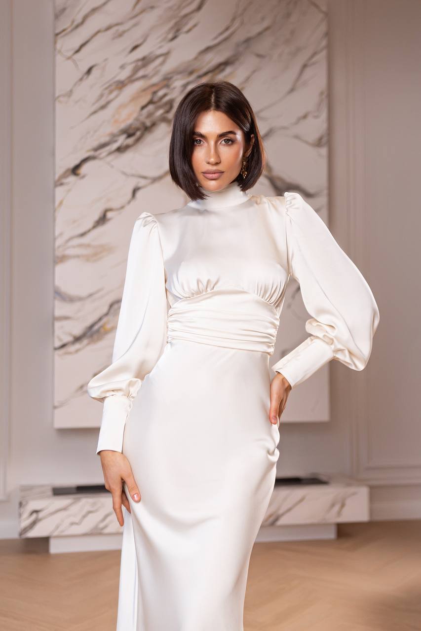 Woman in a white dress standing in a room with marble walls.