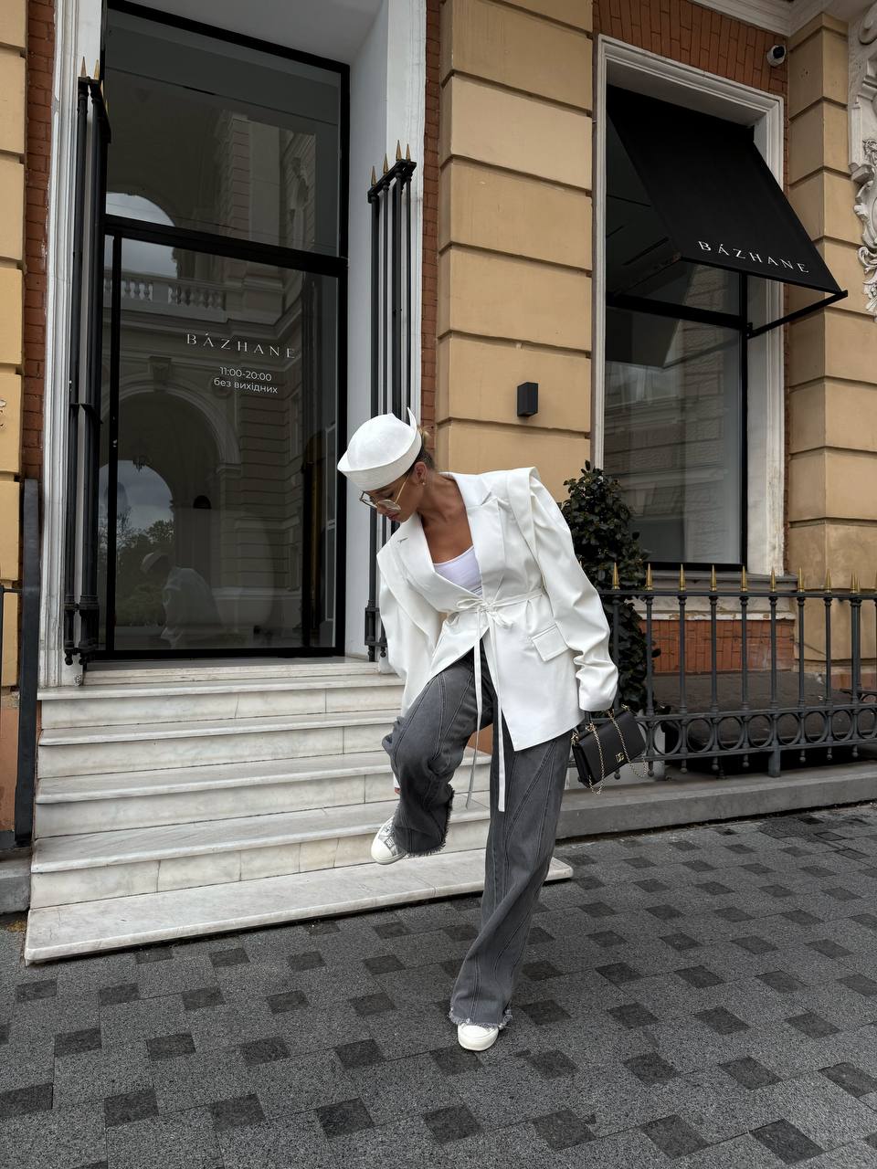 Person in white outfit and hat walking past a building entrance