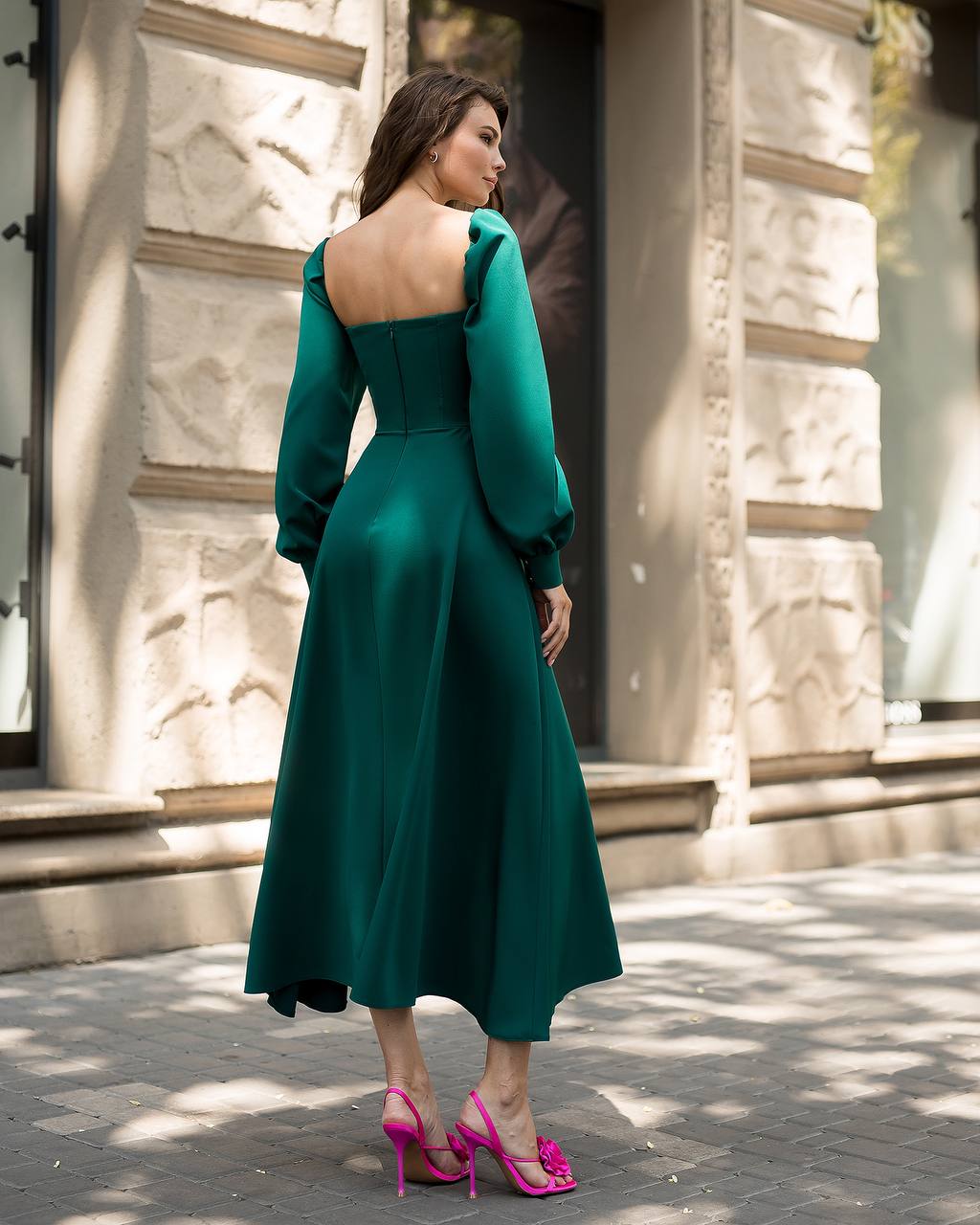 Woman in a green dress standing on a street with a building in the background