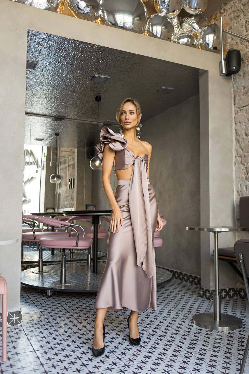 Woman in a stylish outfit standing in a modern restaurant interior.