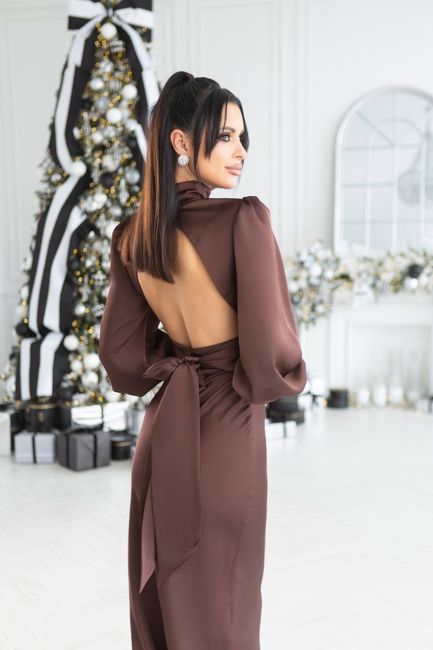 Woman in a brown dress standing in a decorated room with Christmas trees.