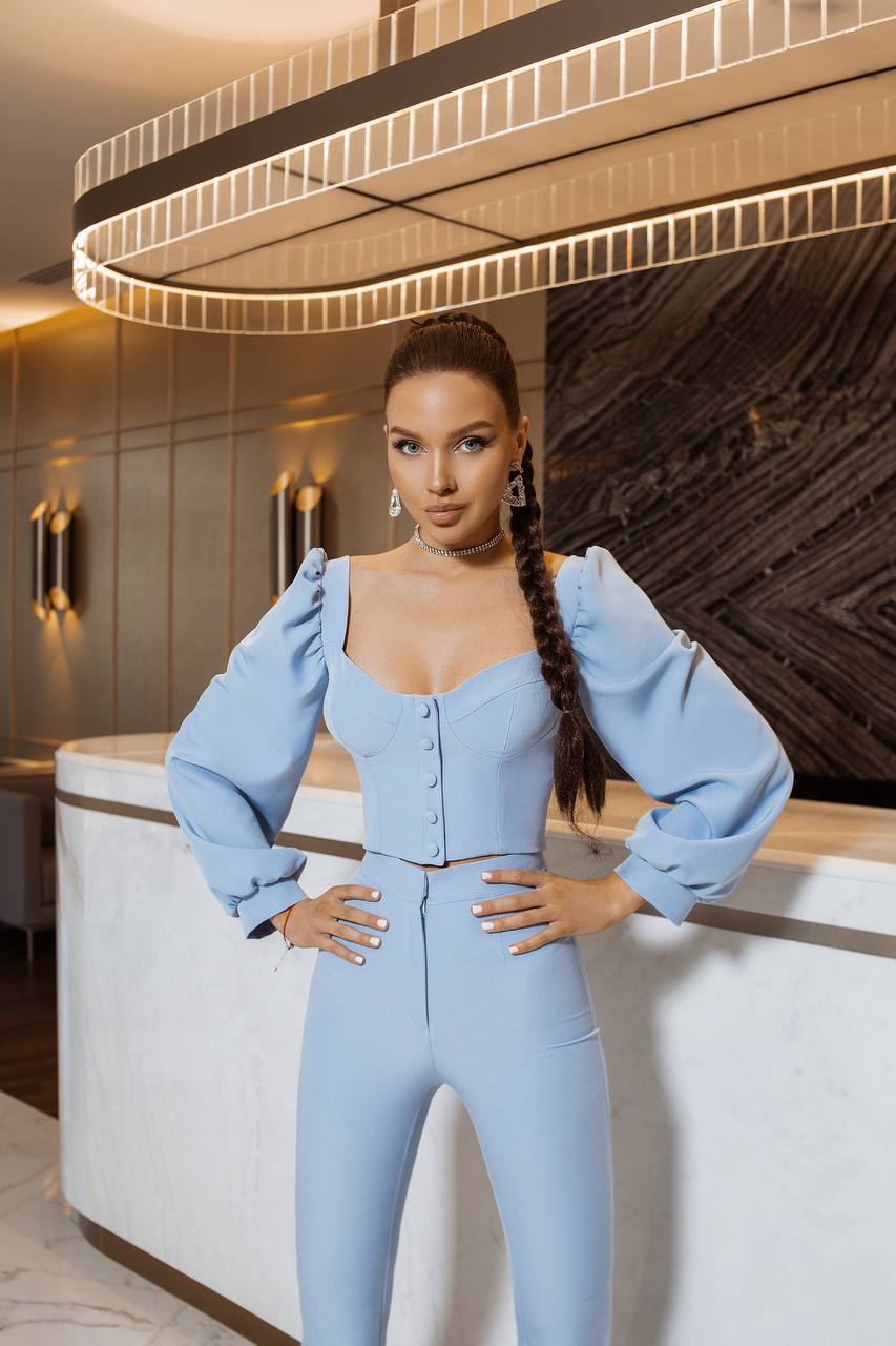 Woman in a light blue outfit posing in an elegant interior setting