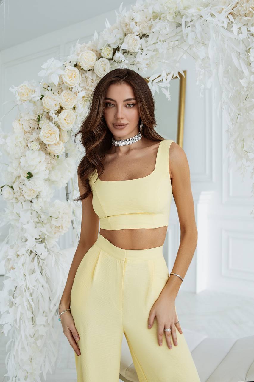 Woman in a yellow outfit standing in front of a floral arrangement