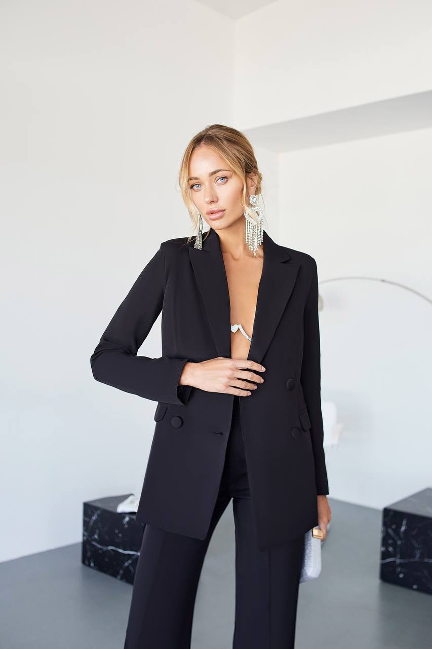 Woman wearing a black suit in a minimalistic setting