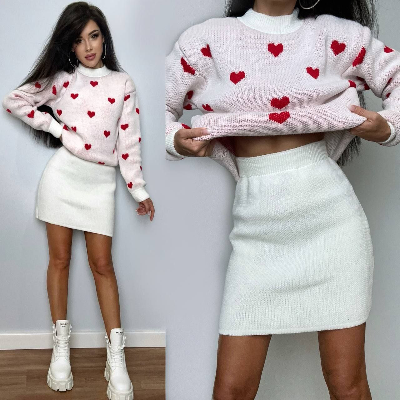 Woman wearing a pink sweater with red heart patterns and a white skirt, holding the sweater.