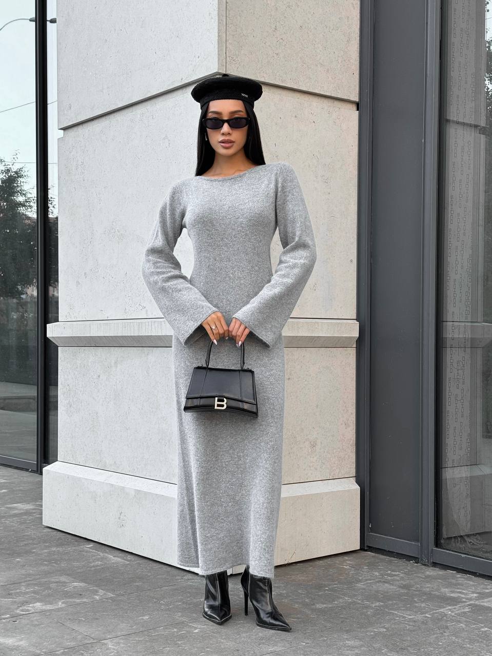 Woman in a gray dress standing against a building