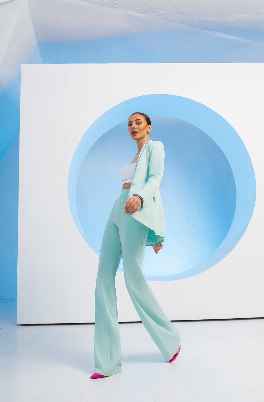 Person wearing a light blue suit standing in front of a circular blue light