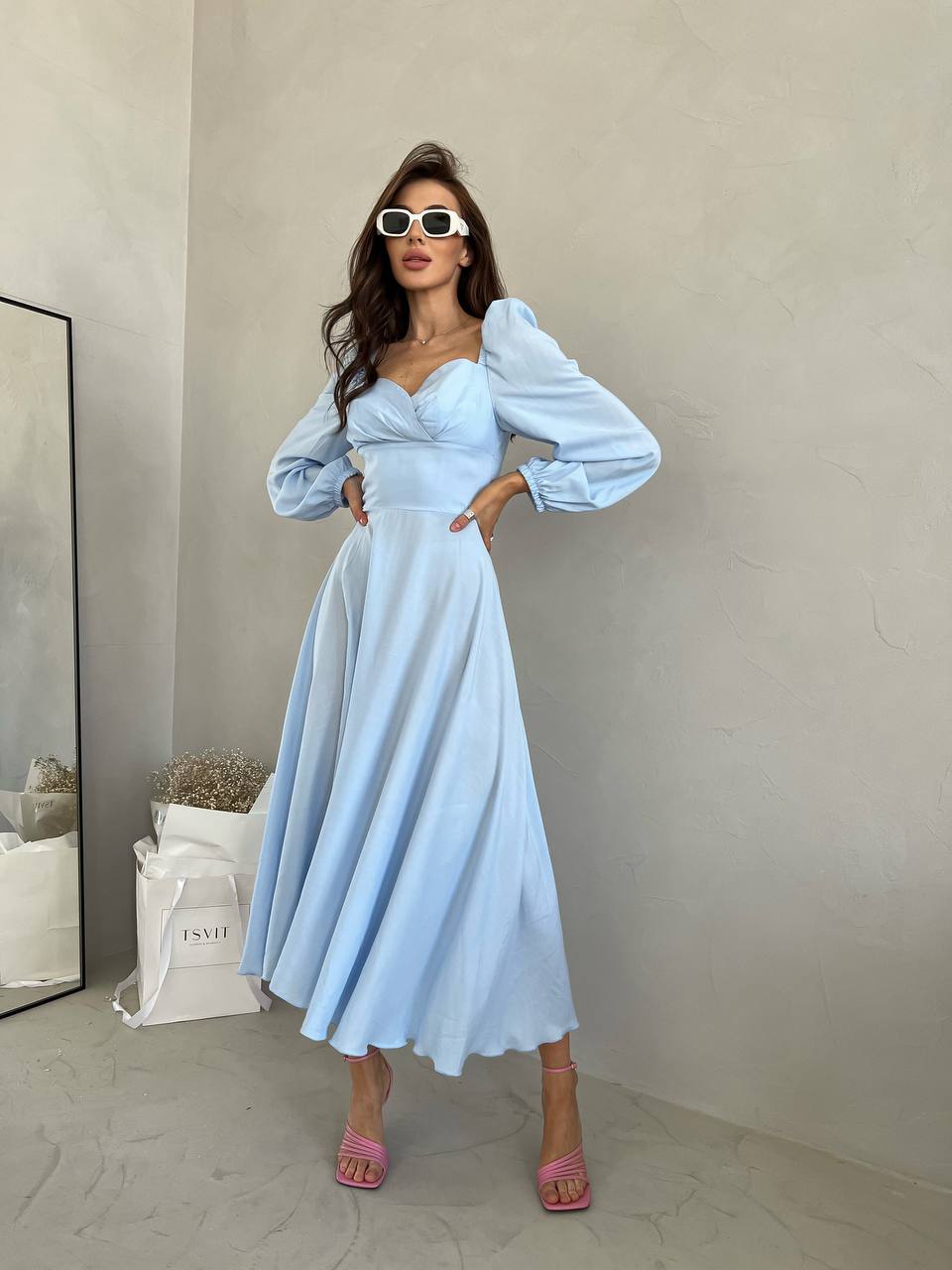 Woman wearing a light blue dress with puffed sleeves in an indoor setting.