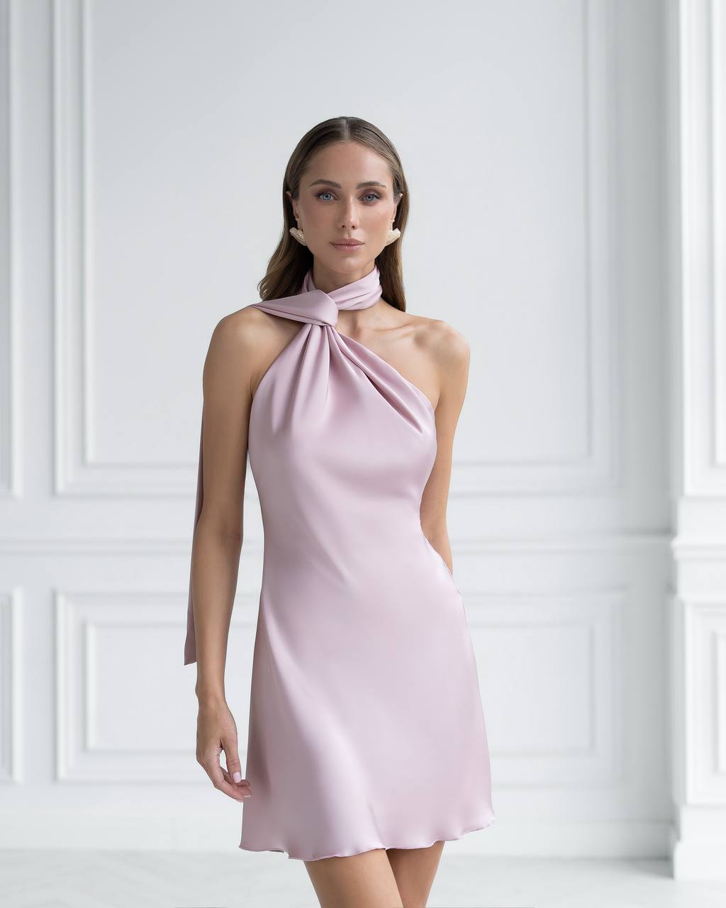 Woman wearing a pink halter neck dress against a white background