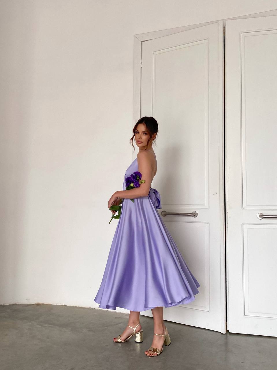 Woman in a purple dress standing in front of a white door.